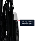 Close-up of a vacuum cleaner showing a black cord, hose, and canister with a white light housing, plus a text callout that reads 'Full Bag or Clog Indicator Light' on a white background.