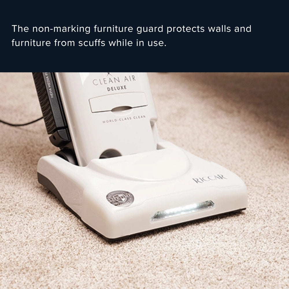 A Riccar Clean Air Deluxe carpet cleaner shown on a beige carpet with a dark navy text banner at the top explaining its non-marking furniture guard.