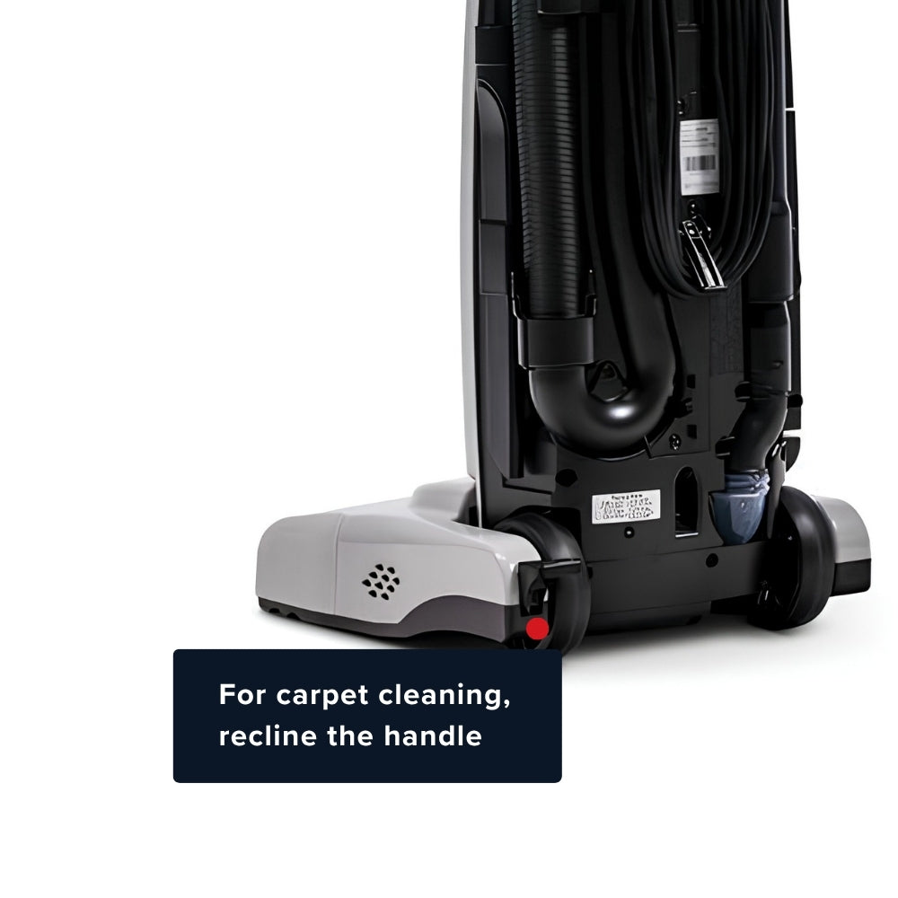A close-up of a vacuum cleaner showing the underside and base, with a text overlay that reads 'For carpet cleaning, recline the handle'. The vacuum has a black body with a gray base and black wheels.